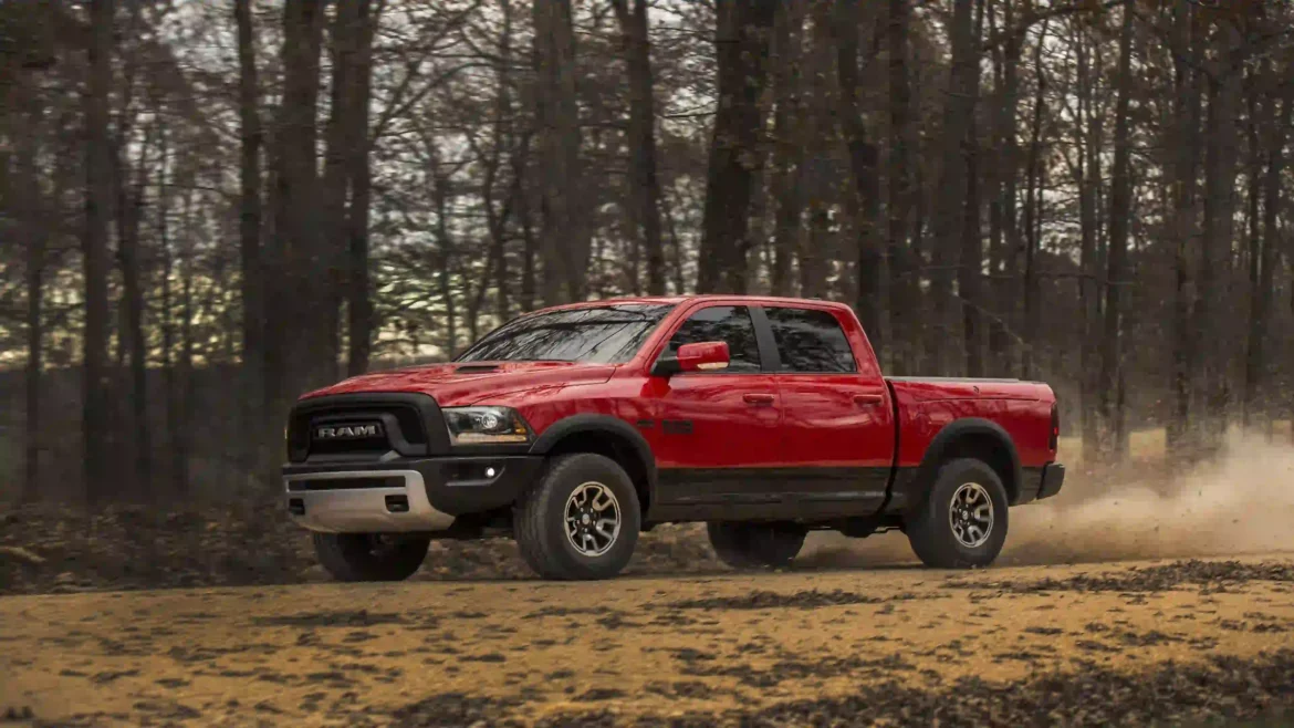 Red Ram 1500 Rebel pickup truck driving fast on a dirt road in the woods kicking up dust automotive wallpaper