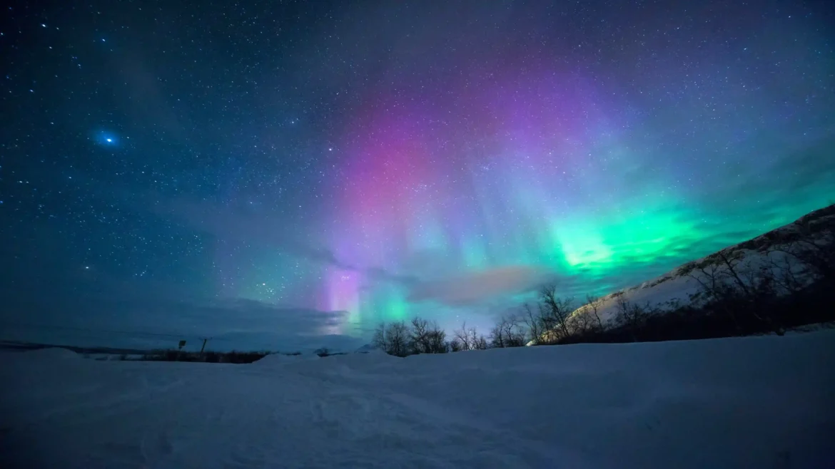 4K wallpaper featuring the colorful Aurora Borealis over a snowy Arctic landscape beneath a star-filled night sky