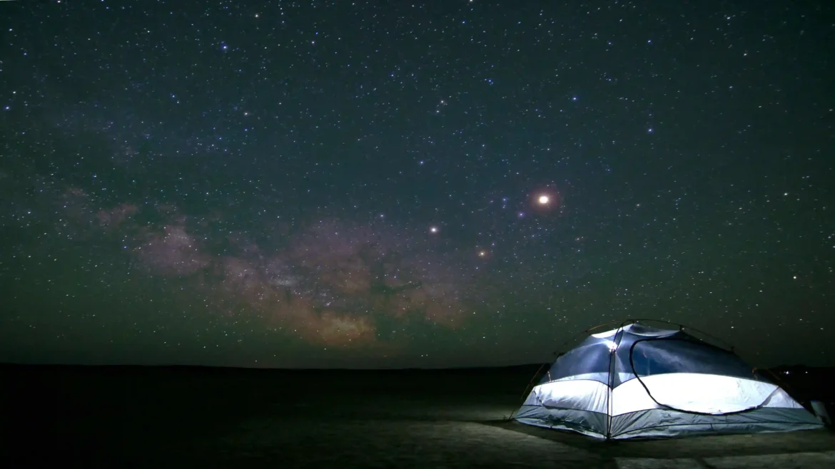 Illuminated camping tent beneath the Milky Way galaxy and a star-filled night sky in Ultra HD 4K