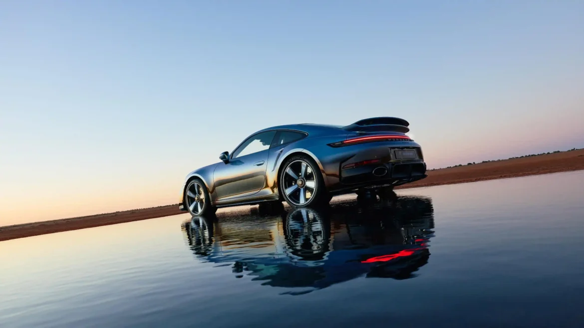 2026 Porsche 911 Turbo S rear view reflected on a calm water surface at sunset in a high-resolution 4K wallpaper