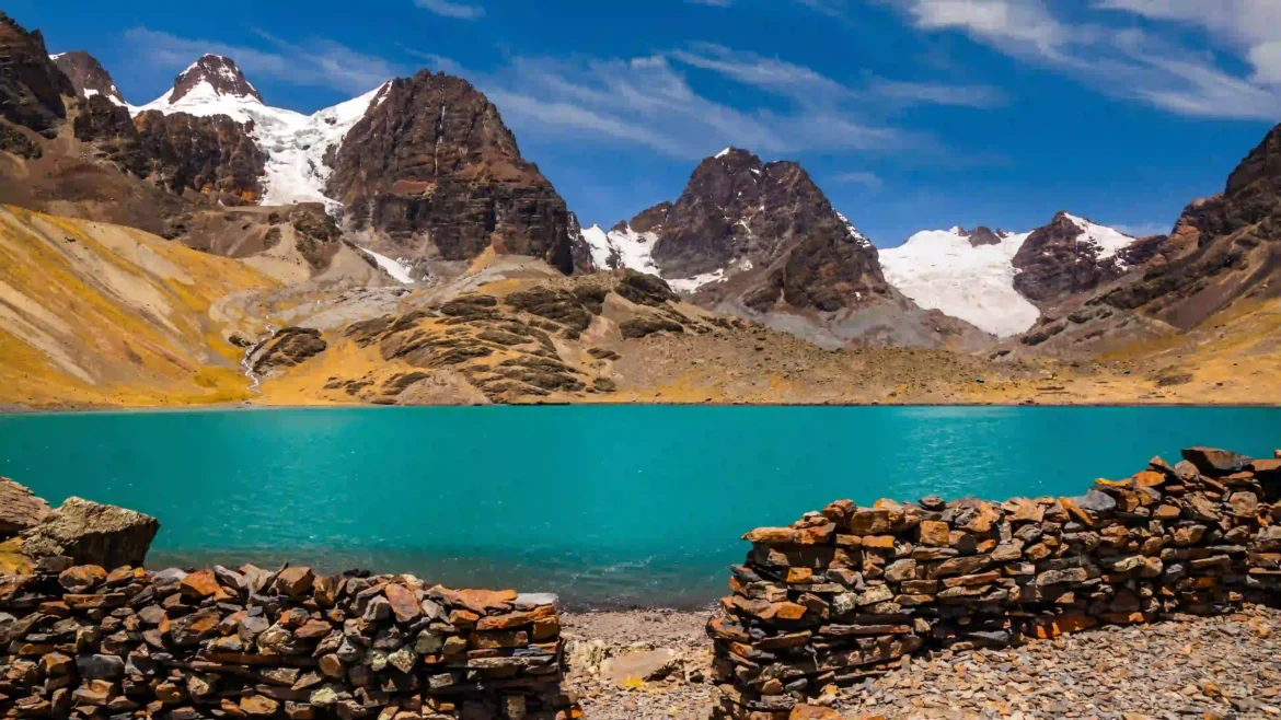 Turquoise glacial lake beneath snow-capped Andean mountains with rocky alpine shores and clear blue sky in an Ultra HD 4K wallpaper