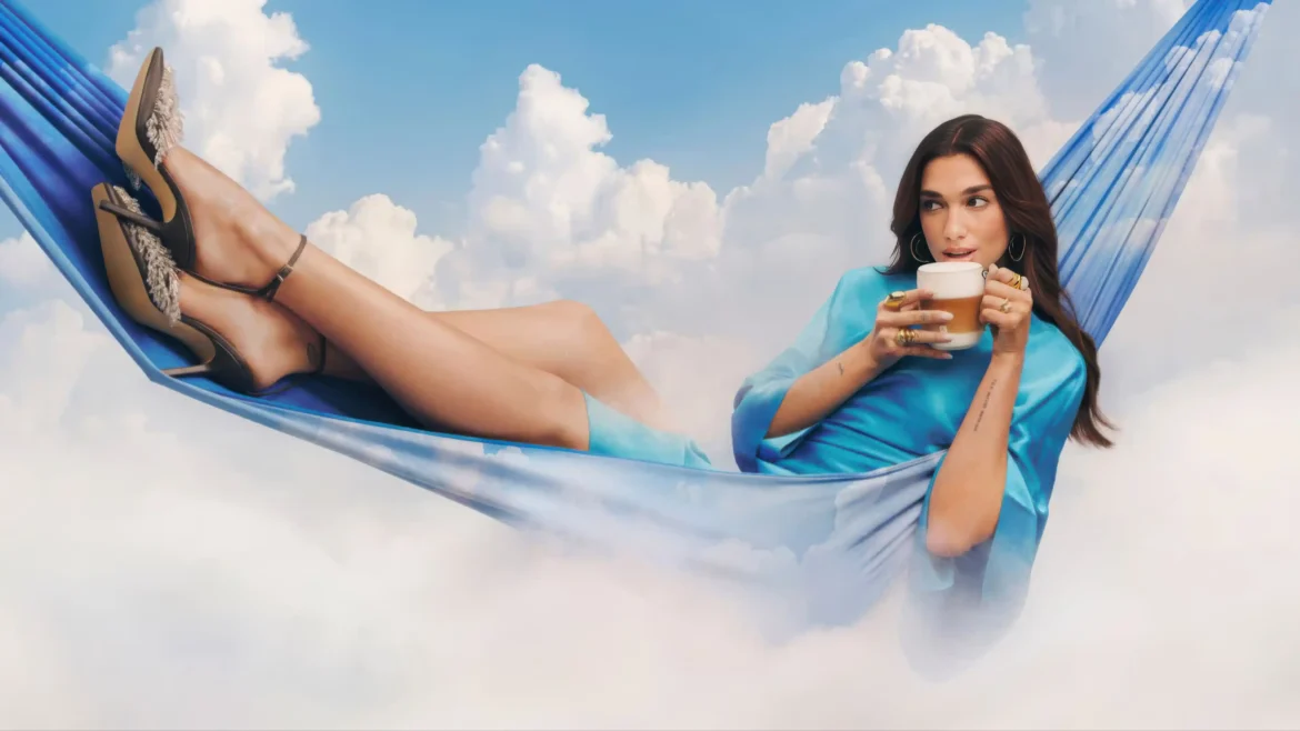 Dua Lipa lounging in a blue hammock holding a coffee glass above clouds in a 4K wallpaper