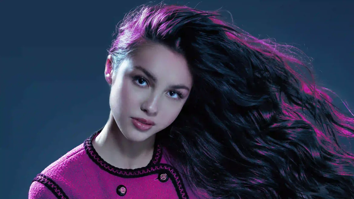 Studio portrait of singer Olivia Rodrigo with flowing dark hair and magenta backlighting wearing a pink jacket for Saturday Night Live in a 4K wallpaper